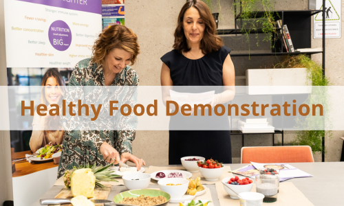 A picture of two ladies demonstrating a food workshop with an opaque banner across the image saying ' A Taste of Wellbeing'